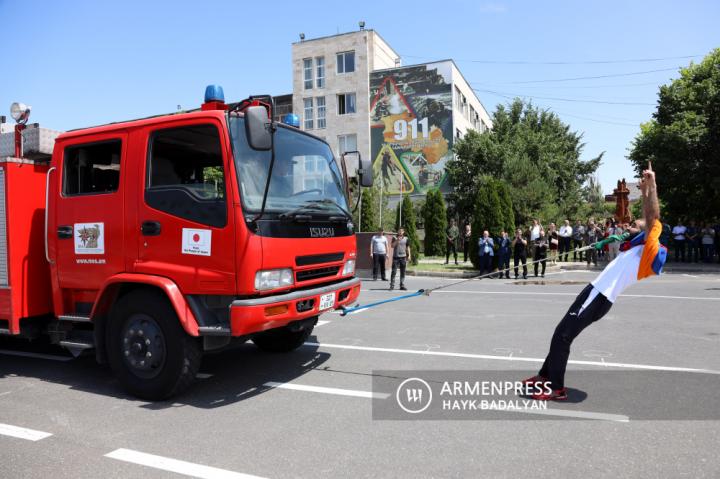 Yuri Sakunts tire deux véhicules de pompiers avec des dents 
cherchant à établir un nouveau record Guinness