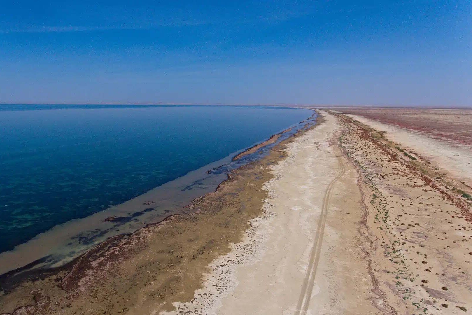 Береговая линия с песчаной дамбой и глубоким синим водным зеркалом &mdash; отчетливо видно разграничение суши и водоёма (Optimism.kz, февраль 2025)
